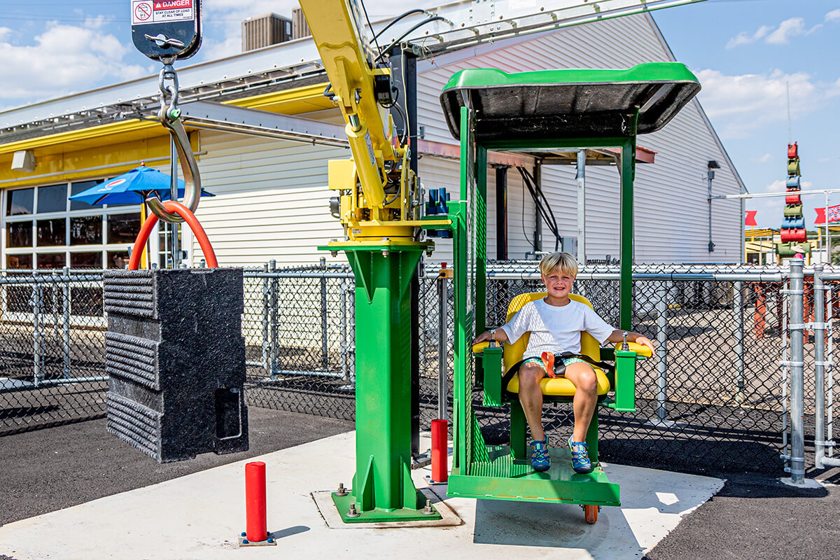 a boy sits in the seat ready to operate a Crazy Crane at Diggerland.